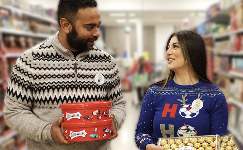 Male and female workers in supermarket holding xmas gifts